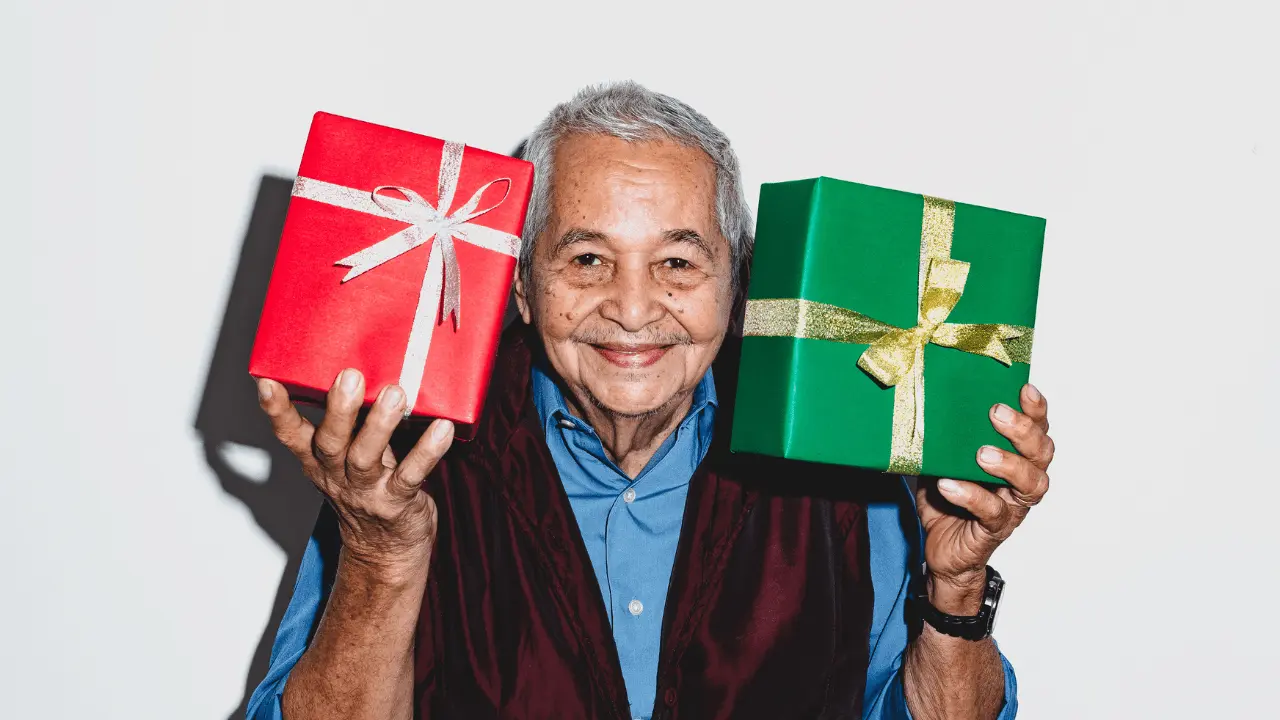 Happy older man holding thoughtful gifts with a smile, showcasing the joy of receiving perfect presents for older men