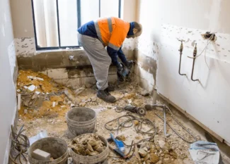 Construction worker renovating a bathroom for seniors, preparing for bathroom upgrades to improve accessibility