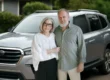Senior couple standing in front of their silver SUV, representing the best SUV for seniors