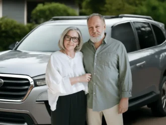 Senior couple standing in front of their silver SUV, representing the best SUV for seniors