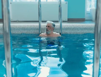 Senior man performing pool workouts for seniors in the water, improving strength and balance