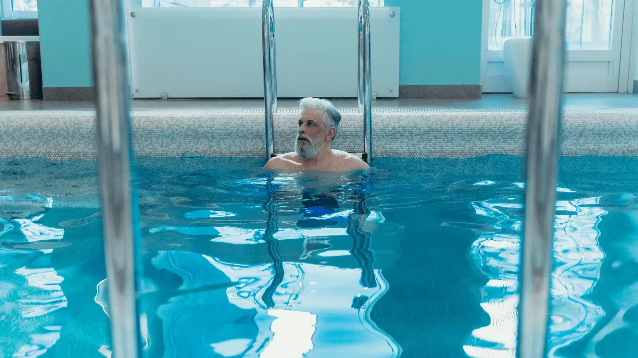 Senior man performing pool workouts for seniors in the water, improving strength and balance
