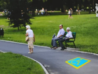 Senior citizens walking in the park with a blue handicapped parking symbol on the path, representing senior parking spot ideas