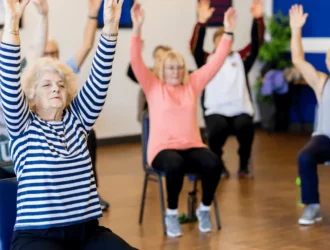 Seniors participating in a seated workout class, lifting their arms in a fitness session.