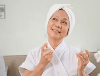 Senior woman applying perfume, enjoying a moment of self-care in a cozy, relaxed setting.