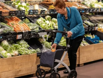 Senior woman selecting fresh vegetables at a grocery store, representing CalFresh benefits for seniors