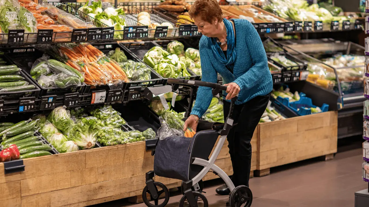 Senior woman selecting fresh vegetables at a grocery store, representing CalFresh benefits for seniors