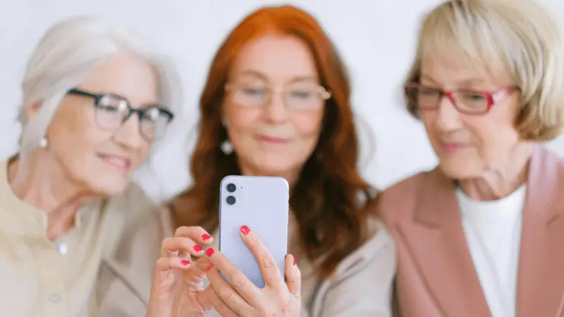 Senior women enjoying using a dating app on their phones, exploring online connections.