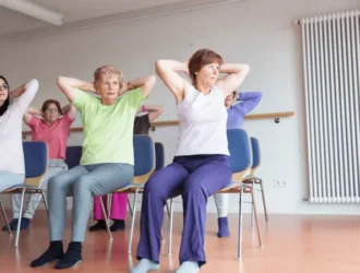 Seniors practicing chair yoga in a class, performing seated exercises to improve posture and flexibility.