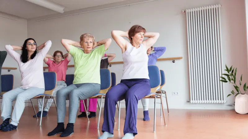 Seniors practicing chair yoga in a class, performing seated exercises to improve posture and flexibility.