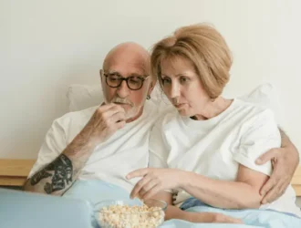 Senior couple watching a movie together at home with popcorn, enjoying streaming services.
