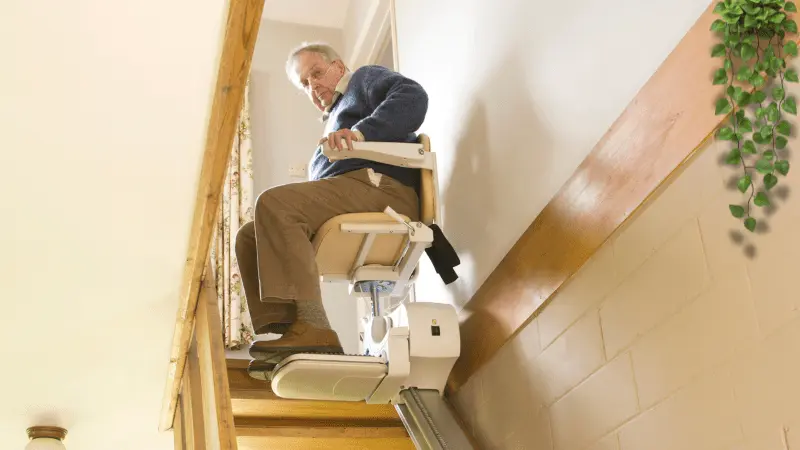 A senior man using a stair lift to move safely upstairs at home, enhancing mobility and independence.