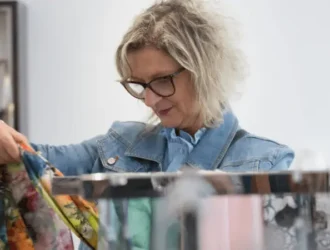Senior woman shopping for clothes, looking at colorful garments in a clothing store, enjoying a shopping experience with discounts for seniors